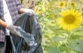 Hand holding plastic bottle waste, picking up trash putting to the black garbage bag at Sunflower Park on Environmental Earth day Royalty Free Stock Photo