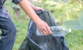 Hand holding plastic bottle waste, picking up trash putting to the black garbage bag at Sunflower Park on Environmental Earth day Royalty Free Stock Photo
