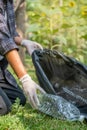 Hand holding plastic bottle waste, picking up trash putting to the black garbage bag at Sunflower Park on Environmental Earth day Royalty Free Stock Photo