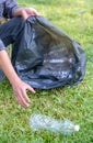 Hand holding plastic bottle waste, picking up trash putting to the black garbage bag at Sunflower Park on Environmental Earth day Royalty Free Stock Photo