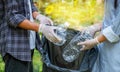 Hand holding plastic bottles waste, Couple picking up trash putting to the black garbage bag at Sunflower Park on Environmental Royalty Free Stock Photo