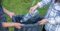 Hand holding plastic bottles waste, Couple picking up trash putting to the black garbage bag at Sunflower Park on Environmental Royalty Free Stock Photo