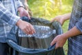 Hand holding plastic bottles waste, Couple picking up trash putting to the black garbage bag at Sunflower Park on Environmental Royalty Free Stock Photo