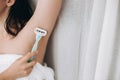 Hand holding plastic razor and shaving smooth armpit. Young woman shaving armpits with plastic razor closeup in home bathroom. Royalty Free Stock Photo