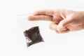 Hand holding Plastic transparent zipper bag with half Brewed coffee powder isolated on white, Vacuum package mockup with red clip.
