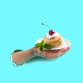 Hand is holding plate of cake through torn paper Royalty Free Stock Photo