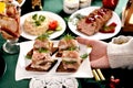 A hand holding a plate with mini canapes with herrings for Christmas to put on festive table