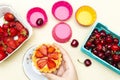 Hand holding a plate of strawberry tart, cherry in basket.