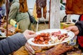 Hand is holding plate with various smoked meat