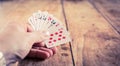 A hand holding playing cards on o vintage wooden table | Gambling | Gambler