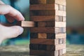 A hand holding and playing Jenga or Tumble tower wooden block game