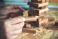 A hand holding and playing Jenga or Tumble tower wooden block game