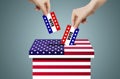 Hand holding and putting voting paper in ballot voting box with USA flag symbol. Royalty Free Stock Photo