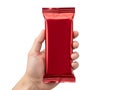 A hand holding a red candy bar wrapper in front of a white background Royalty Free Stock Photo