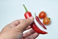 Hand holding red chili and tomato white background