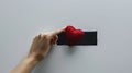 hand holding a red heart-shaped object against a background with a black rectangle in the center.AI generated image Royalty Free Stock Photo