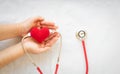 Hand holding red heart and stethoscope on white isolated background. Concept for medical heart health, cardiology, insurance plan Royalty Free Stock Photo