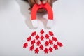 Hand Holding Red Horseshoe Magnet Attracting Red Human Figures