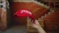 Hand holding red lifeguard hat in indoor construction site with bricks and stairs in background Royalty Free Stock Photo
