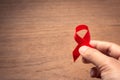 Hand holding red ribbon Aids awareness for World HIV/AIDS day Royalty Free Stock Photo