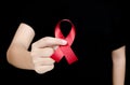 Hand holding red ribbon on black background sign of world aids d