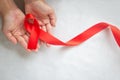 Hand holding Red ribbon on white background with copy space, the solidarity of people living with HIV, AIDS symbol, and for the Royalty Free Stock Photo