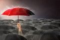 Hand holding red umbrella Among many black umbrellas against the storm, sky background and black cloud group and rain, Royalty Free Stock Photo