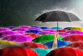 Hand holding red umbrella Among many colorful umbrellas against storm,sky background and black cloud group and rain thunderstorm, Royalty Free Stock Photo