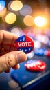 Hand holding a red, white, and blue vote button with stars on a blurred background of bokeh lights Royalty Free Stock Photo