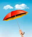 Hand holding a red and yellow umbrella against a blue sky Royalty Free Stock Photo