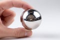 Hand holding a reflective metallic sphere that captures a detailed inverted reflection of the surrounding environment on a clean Royalty Free Stock Photo