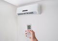 Hand holding remote control for air conditioner on white wall. Royalty Free Stock Photo