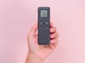 Hand holding remote control isolated on pink background. Remote control in human hand Royalty Free Stock Photo