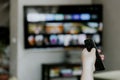 Hand holding remote control pointing to TV. Person watching smart television Royalty Free Stock Photo
