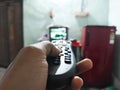 Hand holding remote control while shifting TV channels. Old TV, selective focus blurred background Royalty Free Stock Photo