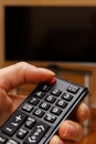 Hand holding remote control for television, choosing channel in TV Royalty Free Stock Photo