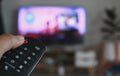 Hand holding remote control of a television. Hands pointing to tv screen set and turning it on or off select channel watching tv Royalty Free Stock Photo