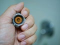 A hand holding a removed / disassembled part of a rain shower head getting clogged with mineral deposits