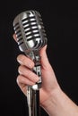 Hand holding a retro microphone over black background Royalty Free Stock Photo