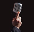 Hand holding a retro microphone over black background Royalty Free Stock Photo