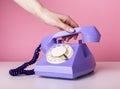 Hand holding retro phone handset, receiver closeup on pink background. Vintage style Royalty Free Stock Photo