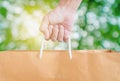 Hand holding reuse paper bag, on green Bokeh and bright yellow light background Royalty Free Stock Photo