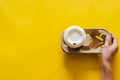 Hand holding reuse paper tray with a recycle cup of coffee on yellow paper background Royalty Free Stock Photo