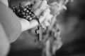 Hand holding Rosary in black and white background. Senior woman holding rosary with open hand with Jesus Christ Cross Crucifix.