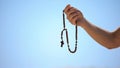 Hand holding rosary, praying to god on blue background, religious spirituality Royalty Free Stock Photo