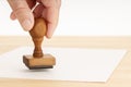 Hand holding a Rubber stamp and blank paper on wooden table Royalty Free Stock Photo