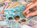 Hand holding 5 rupee coin over Indian rupees, old and new notes, closeup