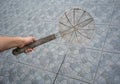 Hand holding rusty cooking strainer with wood handle applied for