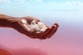 Hand holding salt crystals near pink water surface Royalty Free Stock Photo