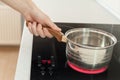 Hand holding a saucepan in modern kitchen with induction stove. Royalty Free Stock Photo